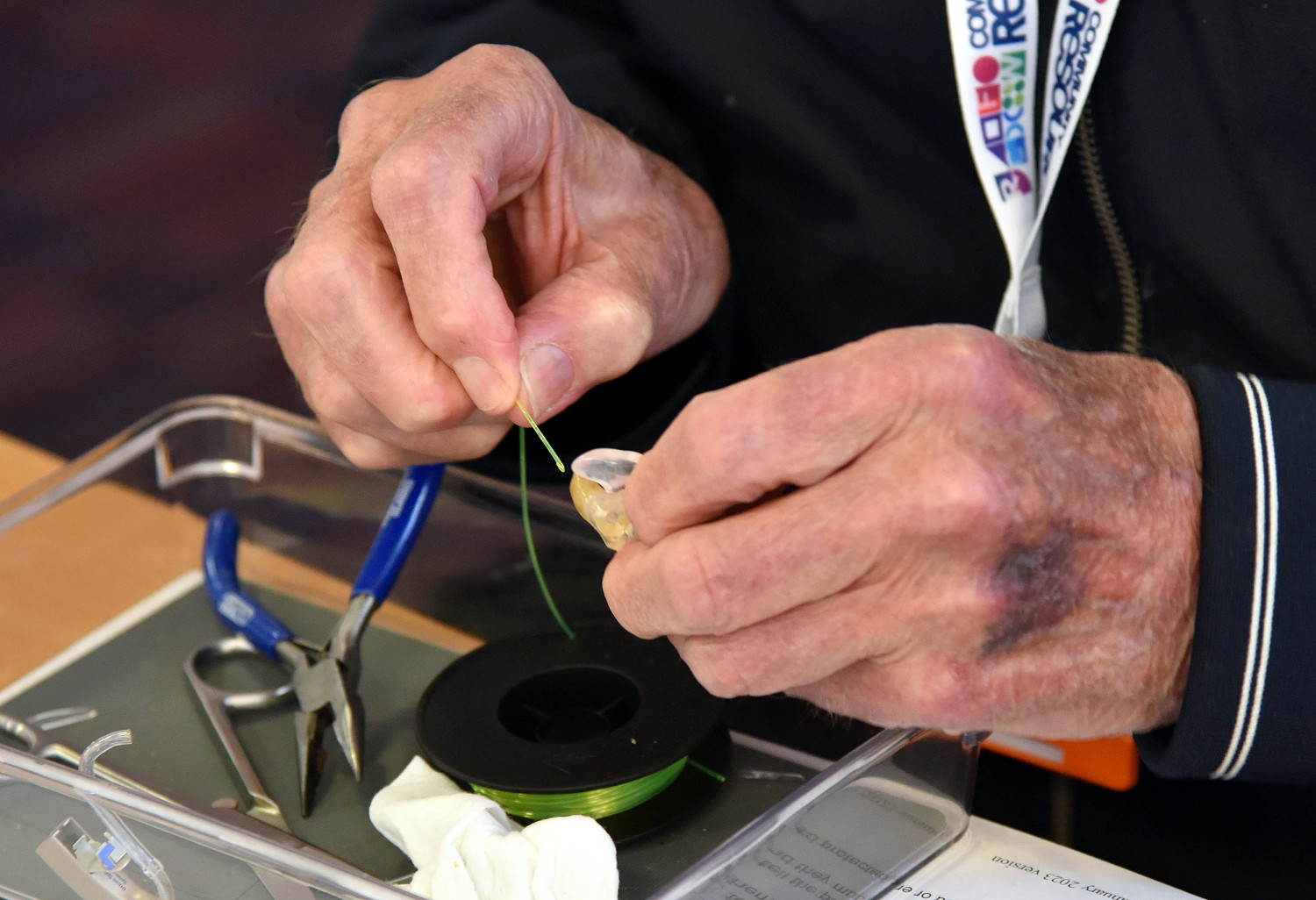 DSC_7372 A man using green wire to clean or repair a hearing aid