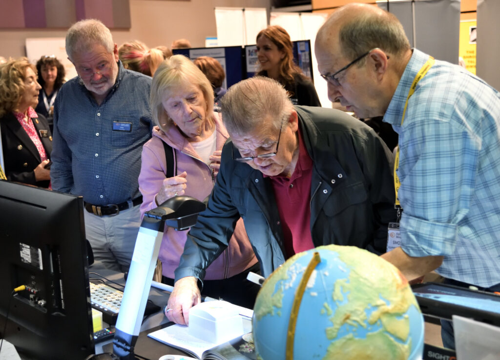 Attendees at the see, hear, remember exhibition engaging with exhibitors.