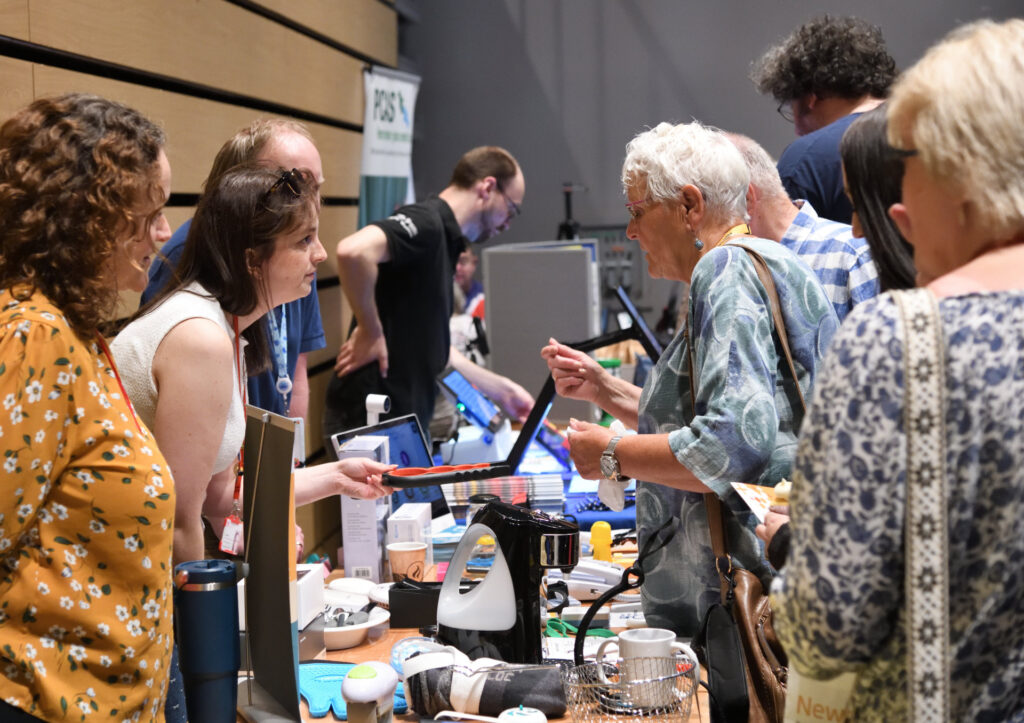 Attendees at the see, hear, remember exhibition engaging with exhibitors.