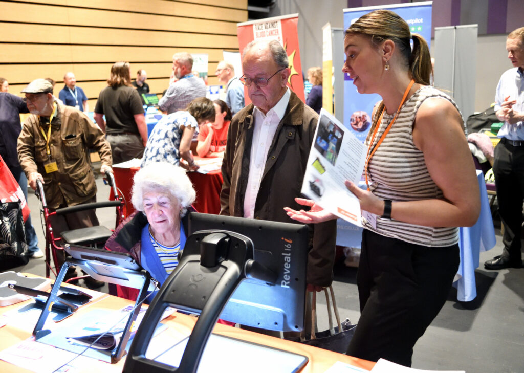 Attendees at the see, hear, remember exhibition engaging with exhibitors.