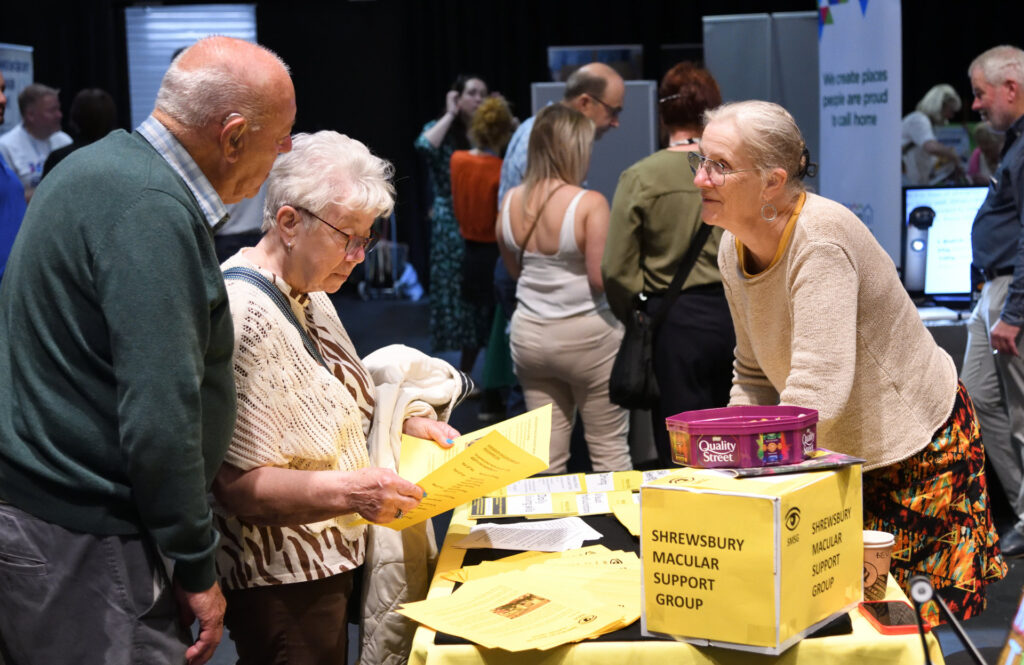 Attendees at the see, hear, remember exhibition engaging with exhibitors.